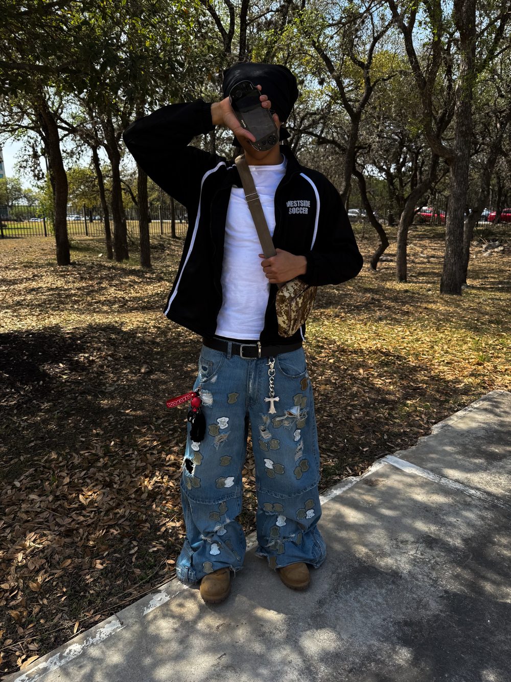 Rio standing in a park, holding a handheld console up over his face